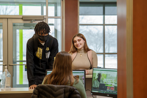 two students stand at welcome desk at Delta College