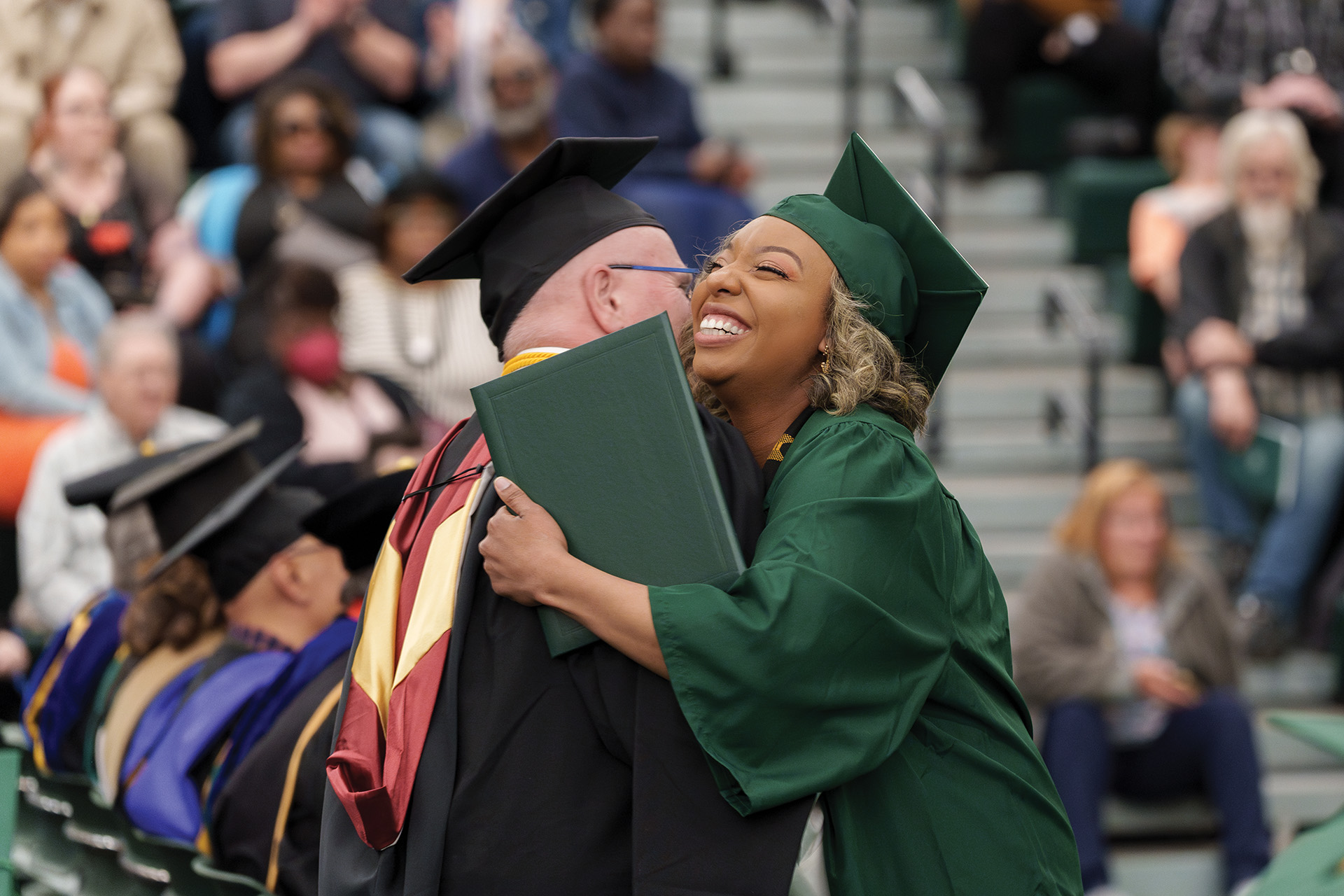 A grad hugging a faculty member